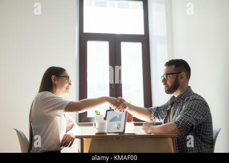 Freundlich tausendjährigen Geschäftsmann und Geschäftsfrau handshaking über Office Tabelle nach angenehmes Gespräch und geschäftliche Verhandlungen. gute Beziehung zwische Stockfoto