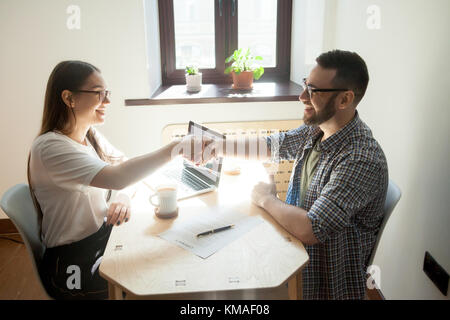 Freundlich tausendjährigen Geschäftsmann und Geschäftsfrau handshaking über Office Tabelle nach der Unterzeichnung Vertrag. Erfolgreiche Arbeit Verhandlungen Stockfoto