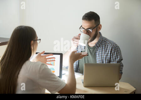 Business Meeting der tausendjährigen Mitarbeiter. schöne Geschäftsfrau in Gläsern erläutert Konzept von Job zu Kollegen. Geschäftsmann hören und Trinken c Stockfoto