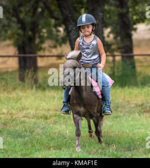 Vierjähriges Mädchen, das auf einem Pony reitet. Stockfoto