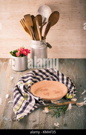 Vertikale Foto von leer Ton Platte auf Holzbrett gelegt mit karierten Tuch angeordnet um. sherley Zweig, Knoblauch, Salz Körner und Gabel neben Stockfoto