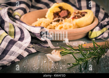 Horizontale Foto von grünen Zweigen, Rosmarin und Knoblauch auf Holzbrett gelegt mit dem verschütteten Salz Körner und vor der dumlings gefüllt Stockfoto