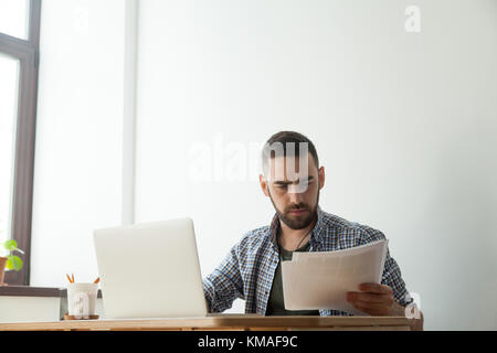 Tausendjährige hipster männlichen Designer holding Pantone Color Swatch Palette. Konzentriert man Arbeiten am Laptop und Home Design Stockfoto