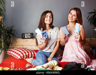 Zwei nette Mädchen holding Pässe und Tickets auf Bett mit Koffer, indoor Travel Concept Stockfoto