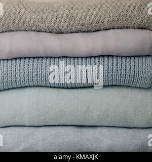 Stapel aus Gewirken Kleider (Pullover, Schals, Pullover) blauen, weißen und grauen Farben. Selektive konzentrieren. Stockfoto