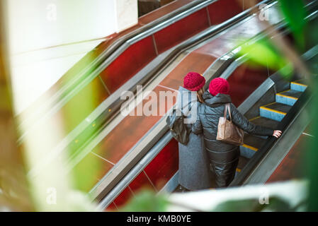 Ansicht von hinten zwei Mädchen an Rolltreppe in der u-bahn Rolltreppe in der U-Bahn. nach oben Treppe. elektrischer Rolltreppe. Blick durch das Grün. Selektive Weichzeichner. Stockfoto