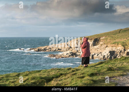 Eine reife Frau alleine stehen an der Küste mit Blick auf die wenig Fistral in Newquay Cornwall im Vereinigten Königreich. Stockfoto