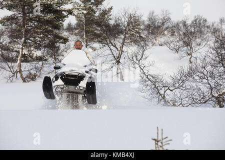 Erwachsener, der mit einem Schneemobile im Schnee auf dem Berg in Norwegen spielt und springt Stockfoto