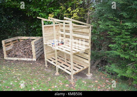 Holz speichern im Bau in Garten mit Kompost aus wieder verwendeten Paletten voller Laub und Grasschnitt auch auf der linken Seite Stockfoto