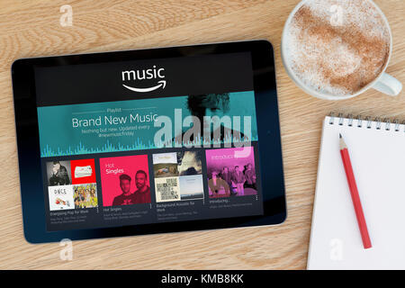 Die Amazon Musik App auf dem iPad Tablet Gerät, das auf einem Tisch liegt neben einem Notizblock und Bleistift und eine Tasse Kaffee (nur redaktionell). Stockfoto