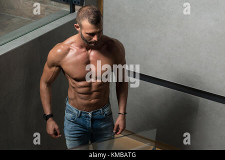 Portrait einer jungen körperlich fit Mann mit seinem Körper beim Tragen blaue Jeans - Muskulös athletisch Bodybuilder Fitness model posing Aft geschult Stockfoto