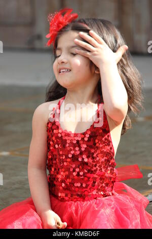 Süße Mädchen im roten Kleid wunderschönes Kind sitzen im Sommer Stockfoto