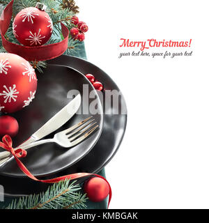 Weihnachtsmenü Konzept mit schwarzem Teller und Besteck dekoriert mit Weihnachtsbaum Zweige und Christbaumkugeln, isoliert auf weißem, text Raum Stockfoto