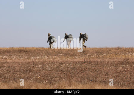 Die Fallschirmjäger der US-Armee kehren nach ihrem Sprung zurück, an der 20. Jährlichen Randy Oler Memorial Operation Toy Drop, veranstaltet von der U.S. Army Civil Affairs & Psychological Operations Command (Airborne), 01. Dezember 2017, in der Sicily Drop Zone in Fort Bragg, North Carolina. Die Operation Toy Drop ist die weltweit größte kombinierte Flugoperation mit neun teilnehmenden Fallschirmjägern der Partnernation und ermöglicht es Soldaten, ihre militärischen Berufsspezialitäten zu trainieren, ihre Flugbereitschaft aufrechtzuerhalten und der lokalen Gemeinschaft etwas zurückzugeben. (USA Armee Stockfoto