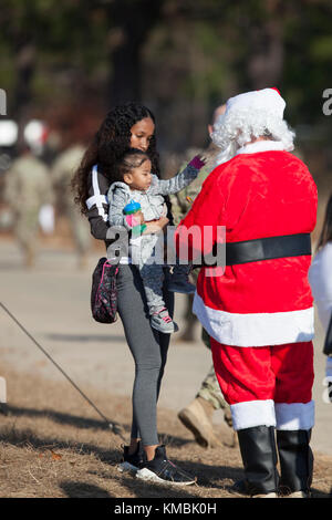 Kinder warten gespannt auf die Ankunft des Weihnachtsmannes, als er aus der Drop-Zone während der 20th Annual Randy Oler Memorial Operation Toy Drop geht, veranstaltet von U.S. Army Civil Affairs & Psychological Operations Command (Airborne), Dez. 01 2017. Die Operation Toy Drop ist die größte kombinierte Luftoperation der Welt mit neun teilnehmenden Partnernationsparatroopern und ermöglicht Soldaten, ihre militärische Berufsspezialität zu trainieren, ihre Luftbereitschaft aufrechtzuerhalten und der lokalen Gemeinschaft etwas zurückzugeben. (USA Armee Stockfoto