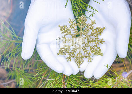 Hände in Handschuhe halten künstliche Schneeflocke Stockfoto