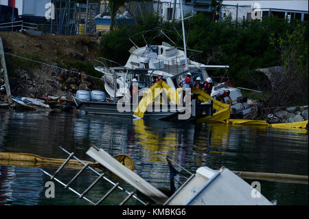 Mitglieder der Küstenwache und ein Auftragnehmer der Umweltschutzbehörde beaufsichtigen das Personal der Resolve Marine Group, einer beauftragten Rettungsfirma, als sie im Rahmen der Mission Emergency Support Function 10 und der Operationen auf St. Thomas, 2. Dezember 2017, von einem verlassenen Schiff in Krum Bay boomen. Die Küstenwache und die EPA koordinieren sich während der ESF-10-Maßnahmen, um die Sicherheit des Personals und den Umweltschutz zu gewährleisten. Küstenwache Stockfoto