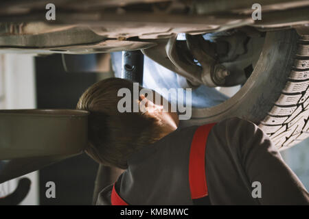 Mechaniker abschrauben Teile des Automobils unter aufgehoben Auto Stockfoto