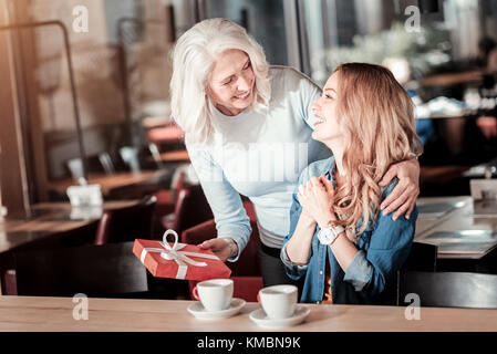 Junge Frau ein hübsches Geschenk ihre liebevolle Oma überrascht Stockfoto