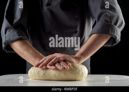 Männliche Hände kneten Sie den Teig für Pizza oder Brot. Stockfoto
