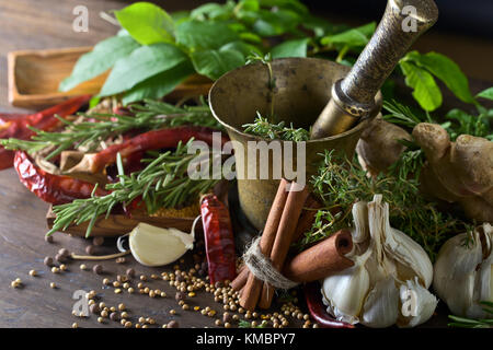 Verschiedene Kräuter und Gewürze auf einem Holztisch. Stockfoto