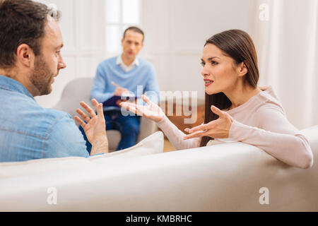 Wütend elegante Frau zeigt Unzufriedenheit zu Mann während der Therapie Stockfoto