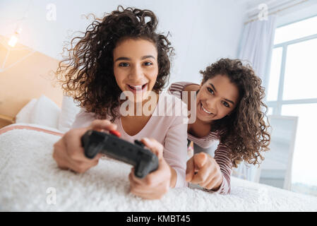 Neugierige junge Damen in casual spielen Videospiele Stockfoto