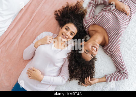 Freudige weibliche Geschwister in der beiläufigen liegend auf Bett Stockfoto