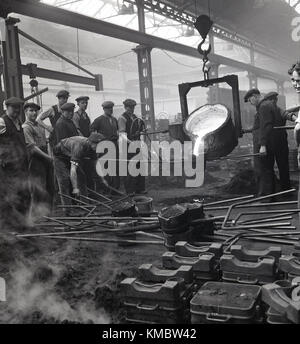 1950, historische, Schiffbau.... eine kleine Gruppe der männlichen Beschäftigten sammeln aound eine Eisen- und Stahlerzeugung geschmolzenen Ofen oder tiegel am Harland und Wolff Werft in Belfast, Nordirland. Beachten Sie, dass Tuch Kappen waren, was diese Zeit getragen wurde, nicht schwer hüten! Stockfoto