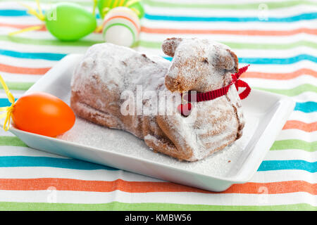 Osterlamm Kuchen mit Puderzucker und roten Herzen auf Kragen, Ostereier beiseite Stockfoto