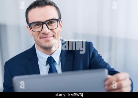 Gerne optimistischer Mann mit Laptop Stockfoto