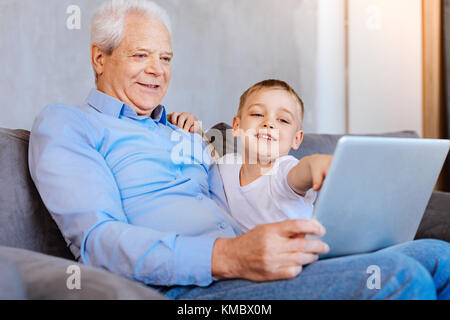 Angenehme älterer Mann am Laptop Bildschirm schaut Stockfoto