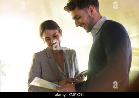 Lächelnder Geschäftsmann und Geschäftsfrau diskutieren Papierkram Stockfoto