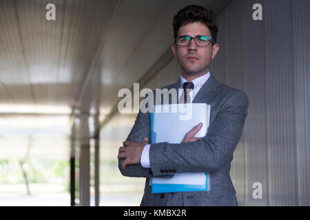 Portrait serious Geschäftsmann hält Papierkram im Bürokorridor Stockfoto