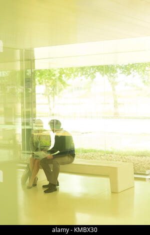 Silhouette Geschäftsmann und Geschäftsfrau im Gespräch auf der Bank im modernen Büro Stockfoto