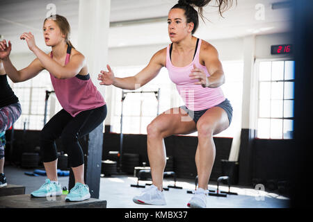 Bestimmte junge Frauen tun Sprung hockt in der Übung Klasse Stockfoto