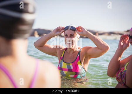 Lächelnd weibliche Open water Schwimmer Waten im sonnigen Ozean Stockfoto