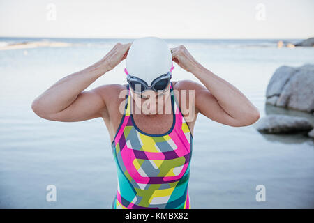 Weibliche Open water Schwimmer einstellen Schwimmbrille im Ocean Stockfoto