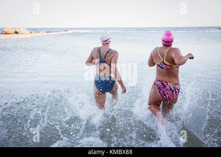 Weibliche Open water Schwimmer laufen und Planschen in Ocean Surf Stockfoto
