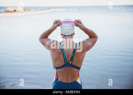 Weibliche Open water Schwimmer einstellen Schwimmbrille im Ocean Stockfoto