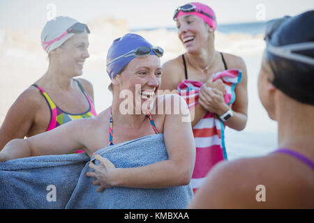 Lachend weiblichen Open water Schwimmer aus Trocknen mit Handtücher Stockfoto