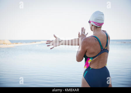 Schwimmerin im offenen Wasser, die Arm und Schulter am Meer streckt Stockfoto