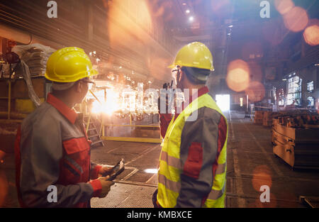 Stahlarbeiter mit Walkie-Talkie beobachten Schweißen in Stahlwerk Stockfoto