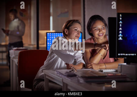 Weibliche Geschäftsfrauen arbeiten spät am Computer im dunklen Büro bei Nacht Stockfoto