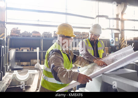 Stahlarbeiter und Ingenieur überprüfen Baupläne in Stahlwerk Stockfoto