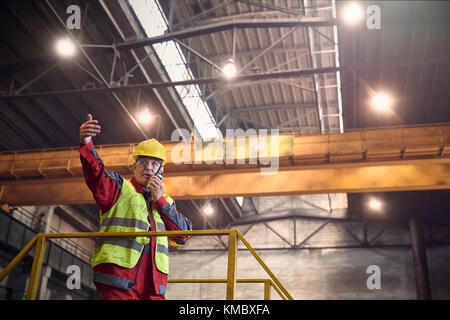 Stahlarbeiter sprechen, mit Walkie-Talkie auf Plattform in Stahlwerk Stockfoto