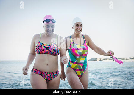 Lächelnde weibliche Schwimmer im offenen Wasser watend im Meer Stockfoto