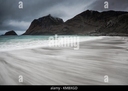 Verschwommene Bewegung Meeresstrand Gezeiten unter zerklüfteten Bergen, Haukland Strand, Lofoten, Norwegen Stockfoto