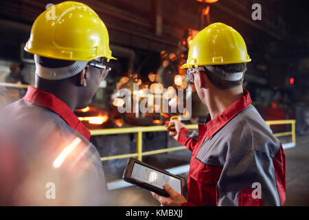 Supervisor und Stahlarbeiter mit digitalem Tablet, das in Stahl arbeitet Mühle Stockfoto
