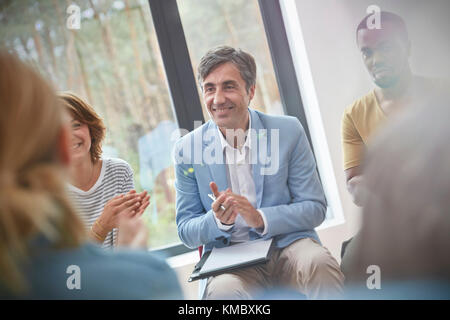 Lächelnder Mann klatscht in der Gruppentherapie Stockfoto